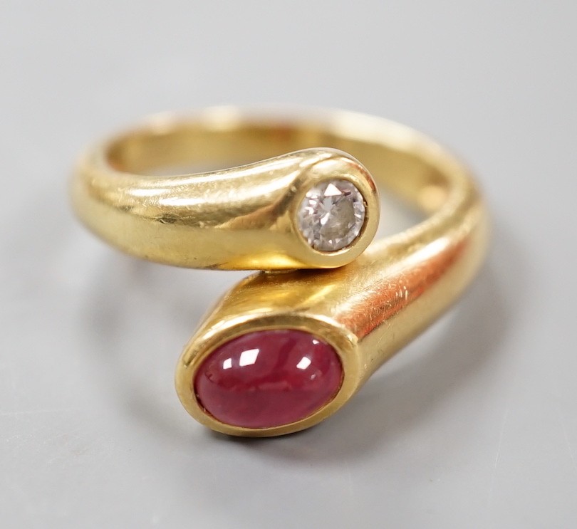 A modern 18k, cabochon ruby and round cut diamond set crossover ring, size N, gross weight 6.8 grams.